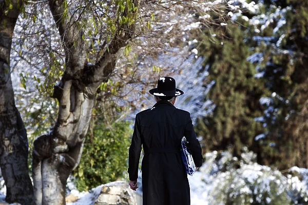 An Ultra-Orthodox Jewish man walks on a snow-covered street near Jerusalems Old City