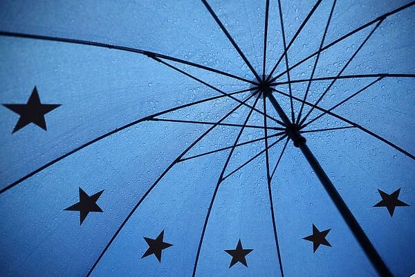 An umbrella with the pattern of the EU flag is seen outside the Houses of Parliament