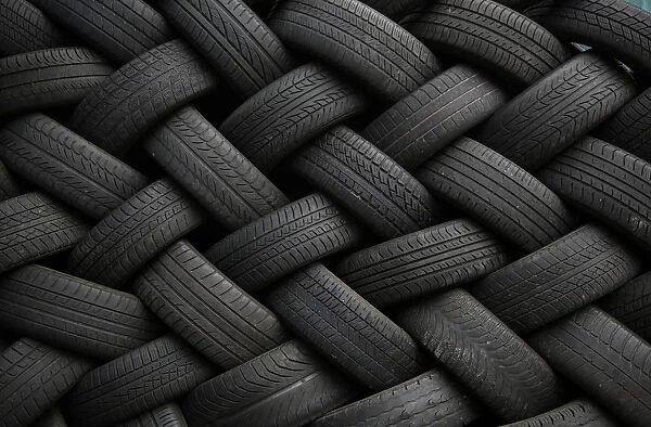 Used car tires form a pattern as they are seen stacked outside an automotive shop in East Dulwich