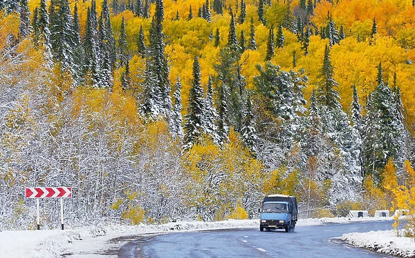 A van drives on a road through a snow covered forest near the Siberian village of