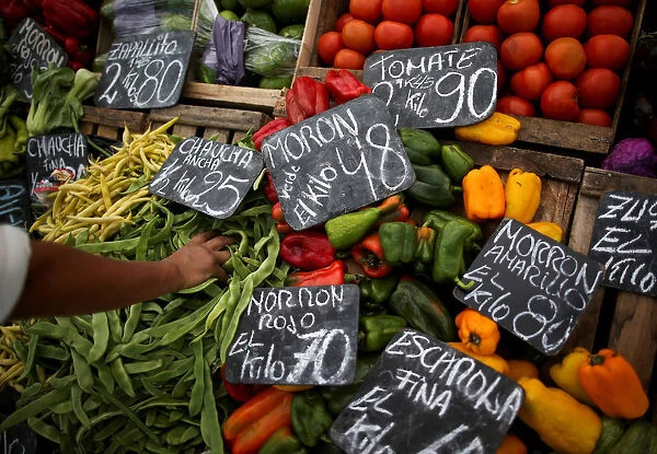 A vegetable seller grabs a handful of indian beans at a street market, in Buenos Aires