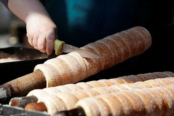 A vendor prepares a traditional Trdelnik sweet pastry in Prague