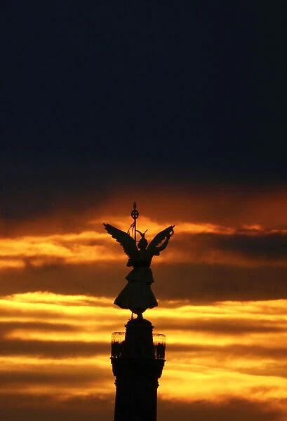 The Victory Column is silhouetted against the sky as the sun sets in Berlin