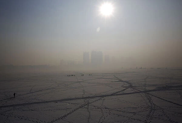 A view of Harbin surrounded by fog is seen over the frozen Songhua River in the northern