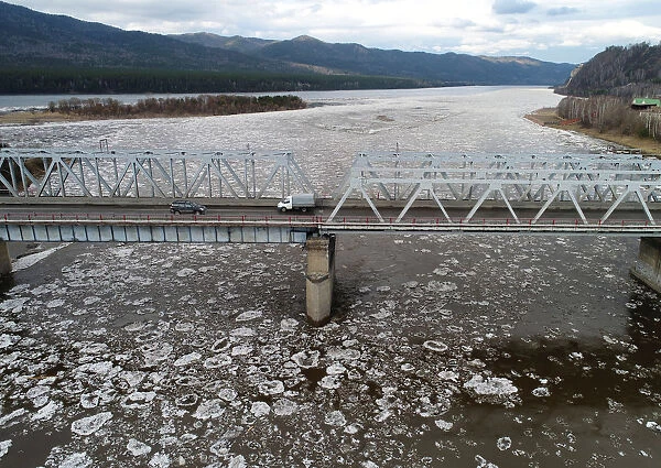 A view shows vehicles driving along a bridge across the Mana River during an ice drift