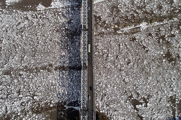 A view shows vehicles driving along a bridge across the Mana River during an ice drift