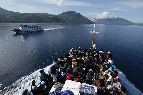 Villagers ride on a wooden boat with their motorcycles towards Adonara, off Flores island