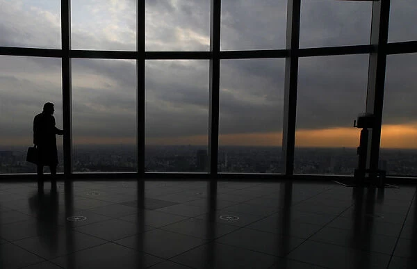 A visitor is silhouetted at an observation deck in Tokyo