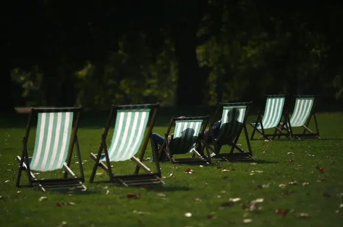 Framed Print : Visitors enjoy the autumn sunshine as they sit in deck chairs in St James Park, central Framed Print : Visitors enjoy the autumn sunshine as they sit in deck chairs in St James Park, central