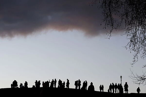 Visitors to Primrose Hill take in the early evening views over central London