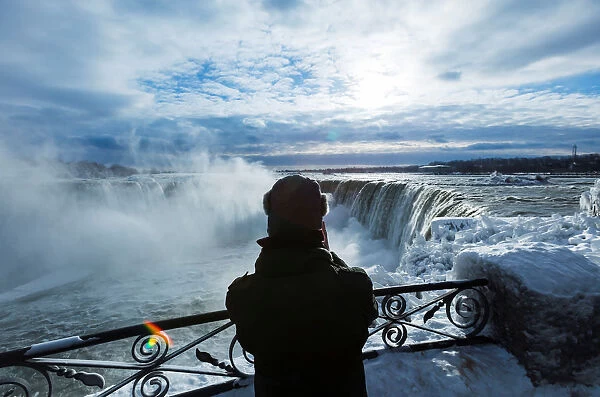 A vistor takes pictures of ice covered Niagara Falls in Niagara