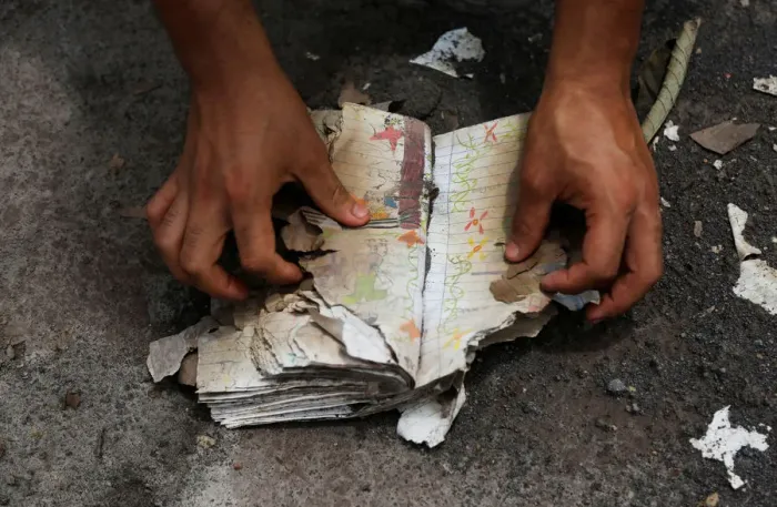 Framed Print : A volunteer looks at a notebook with annotations recovered in an area affected by Framed Print : A volunteer looks at a notebook with annotations recovered in an area affected by