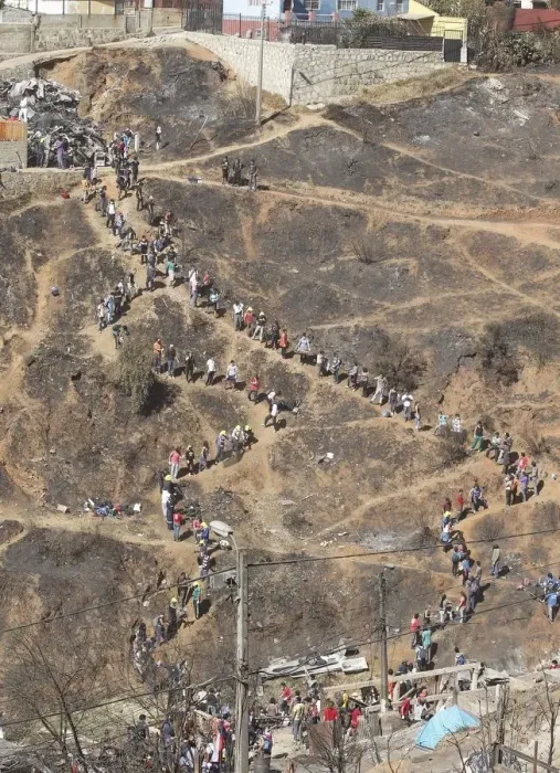 Framed Print : Volunteers form a line as they pass down debris from burned houses after a fire burned Framed Print : Volunteers form a line as they pass down debris from burned houses after a fire burned