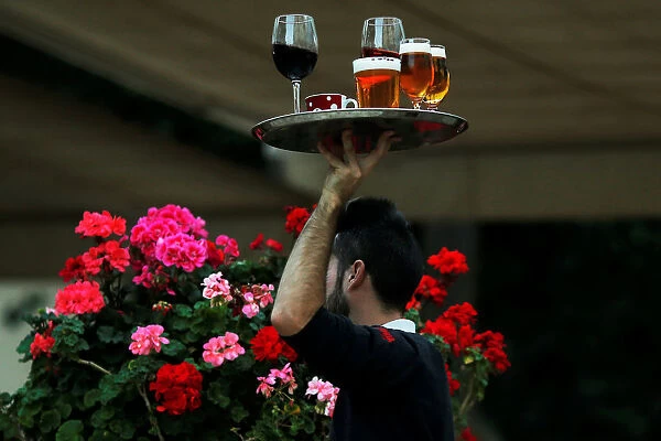 A waiter carries a tray with drinks at the terrace of a restaurant in downtown Malaga