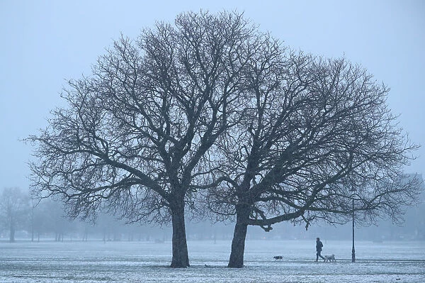 A walker crosses a snow-covered Clapham Common in London