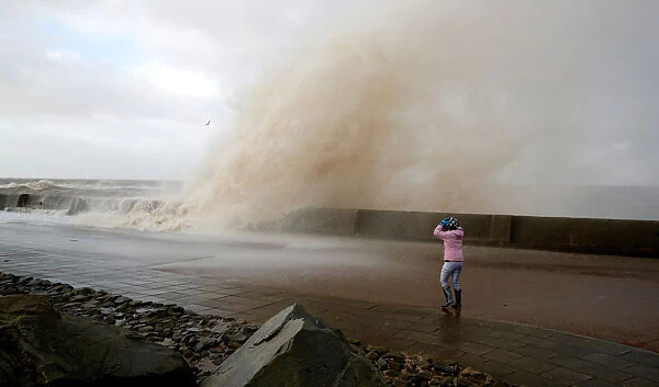 A walker watch the waves breaking in New Brighton, on the coast of the Wirral peninsula