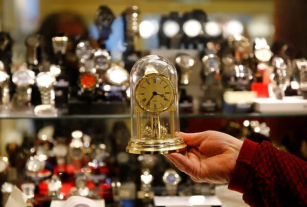 A watchmaker holds a clock in his store in Vienna