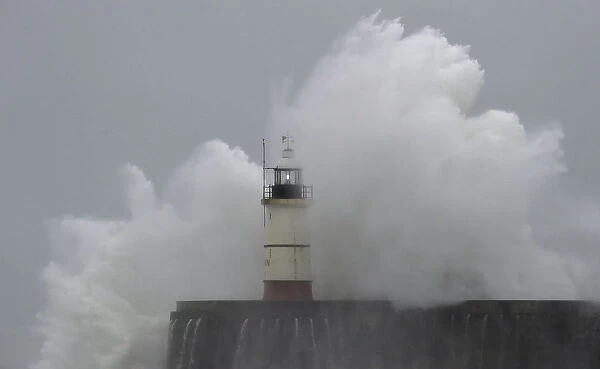 Waves crash against the harbour wall and light beacon at Newhaven in southern England