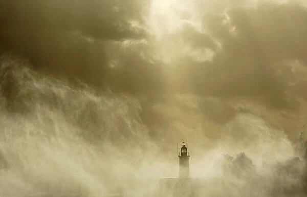 Waves crash against a lighthouse at Newhaven on the Sussex coast in southern England