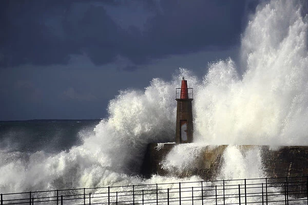 Waves crash against a lighthouse in Viavelez
