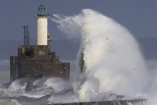 Waves crash against a lighthouse as the wind blows at around 100 kph (62 mph)