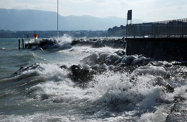 Waves splash on the shore during a windy winter day near Lake Leman in Geneva