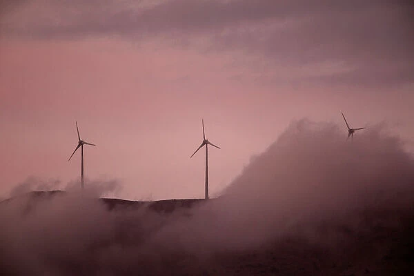 Wind turbines operate atop a mountain during sunset near the town of Kalavrita