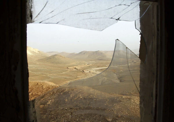 A window with broken glass overlooks the Lebanese-Syrian border as seen from a Lebanese
