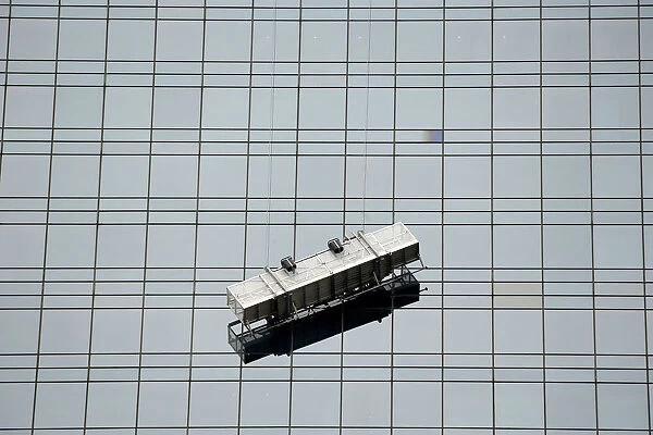 A window washing scaffolding unit hangs precariously from a skyscraper at Columbus Circle