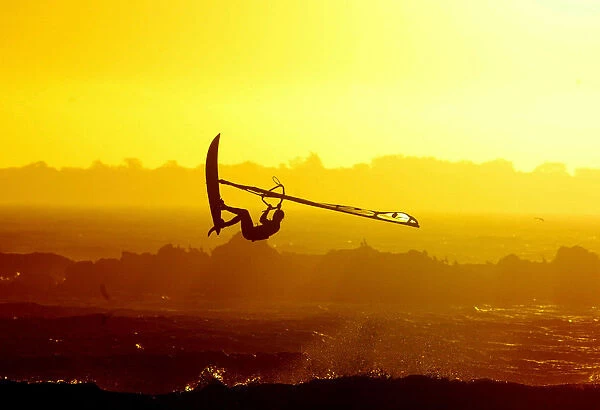 WINDSURFERS GETS AIRBOURNE AS THE SUN SETS ON CAPE TOWN'S BLAAUBERG BEACH