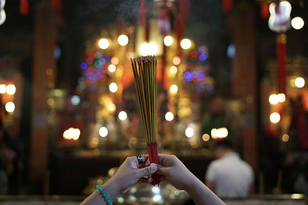 A woman burns incense as she prays at Man Mo Temple in Hong Kong