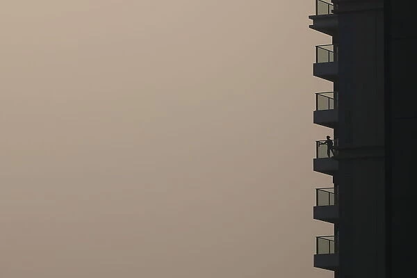 A woman cleans glass panel on a residential building during a hazy day in Shanghai