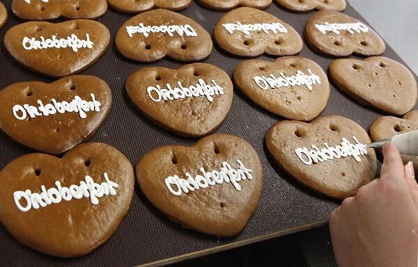 Woman decorates gingerbread Oktoberfest hearts in Zuckersucht bakery in Aschheim