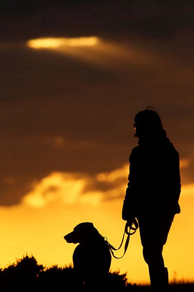 A woman and her dog wait to watch the sunset at Anchor Bay outside Mellieha