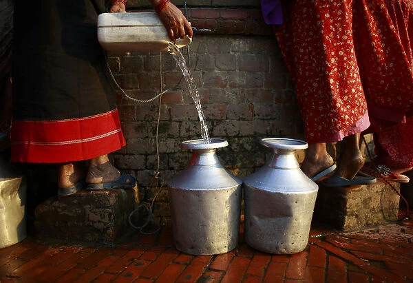A woman fills her pot with water after pulling it out from an almost dried well in
