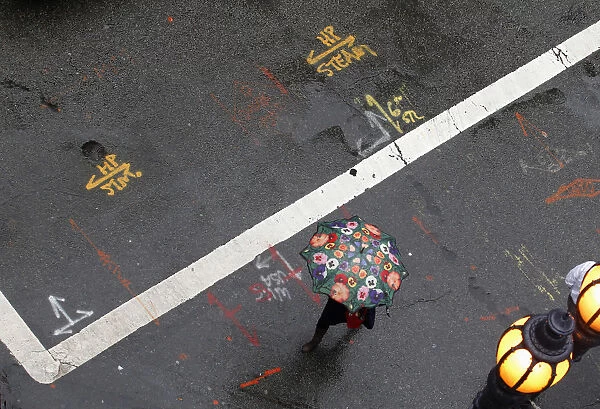 A woman with a flower umbrella crosses the street during a rain storm in San Francisco