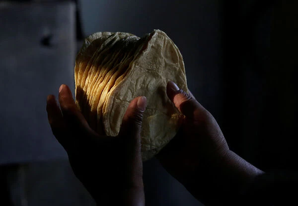 Woman holds freshly made corn tortillas at a tortilla factory in Mexico City