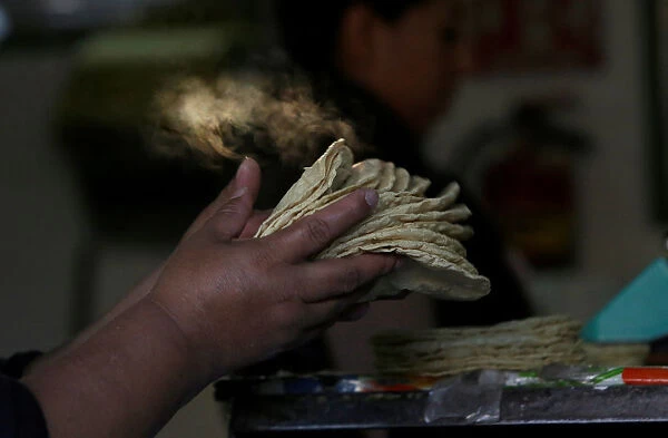 Woman holds freshly made corn tortillas at a tortilla factory in Mexico City