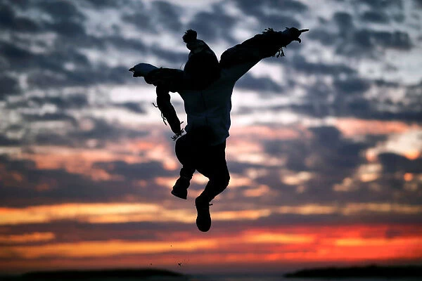 A woman jumps after sunset, along the shore of the Mediterranean Sea in Ashkelon