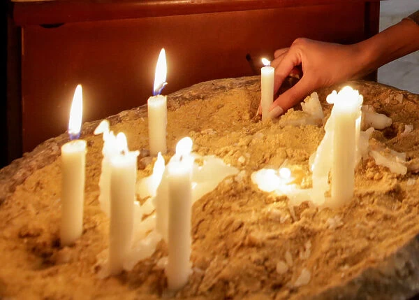 A woman lights a candle at the Orthodox church in Cairo