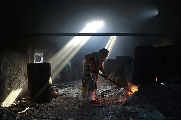 A woman lights fire to heat water for soaking clothes at a laundry in Mumbai
