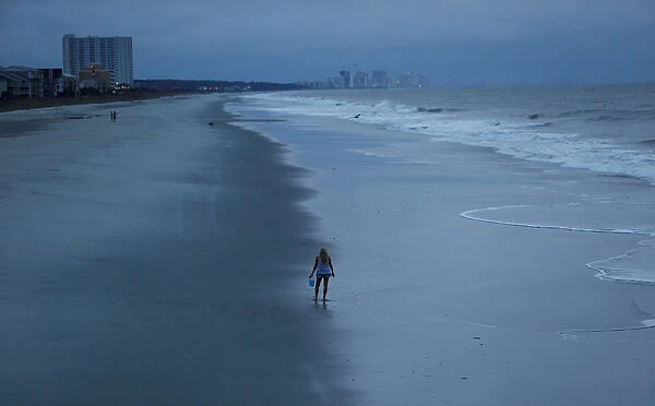 A woman looks for shells ahead of the arrival of Hurricane Florence in Surfside Beach