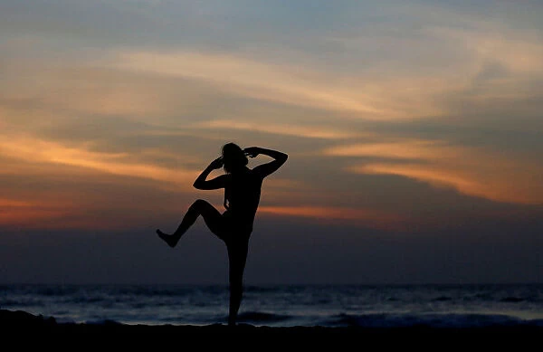 A woman performs yoga on a beach in Colombo
