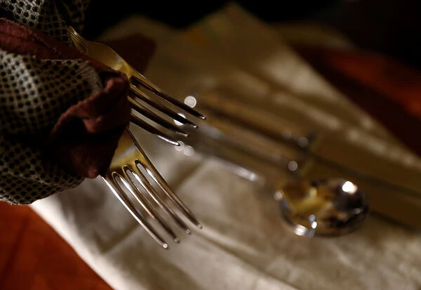 A woman polishes silver cutlery at her home in Valletta