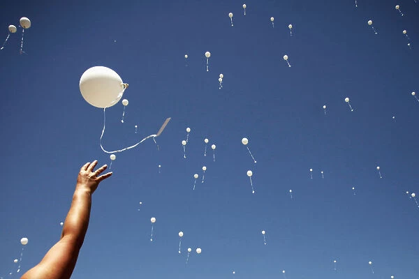 A woman releases a balloon into the air during the 20th anniversary of the closure