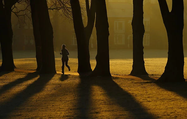 A woman runs through Victoria Park at sunrise in Leicester