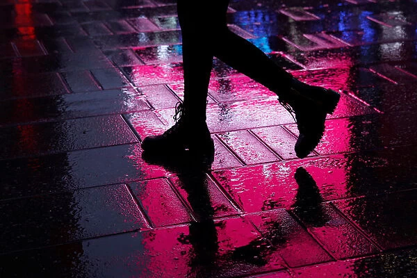 A woman is seen walking through a rain soaked sidewalk at Times Square in New York