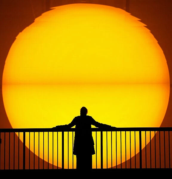 A WOMAN IS SILHOUETTED AGAINST A GIANT SUN IN THE TURBINE HALL AT LONDON S