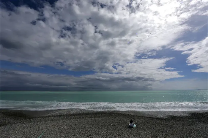 Framed Print : A woman sits on the beach on the Promenade des Anglais in Nice Framed Print : A woman sits on the beach on the Promenade des Anglais in Nice