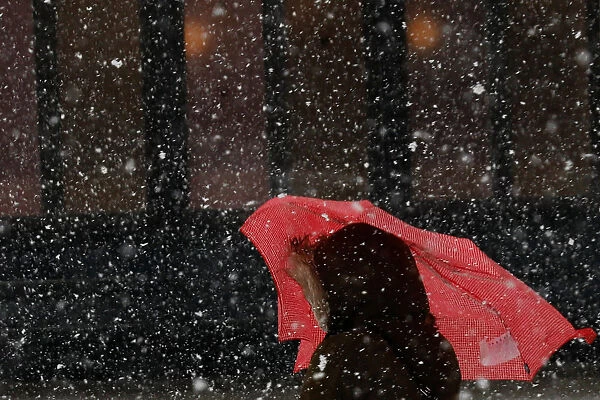 Woman stands with an umbrella during a nor easter at the Brooklyn Bridge Park in New York
